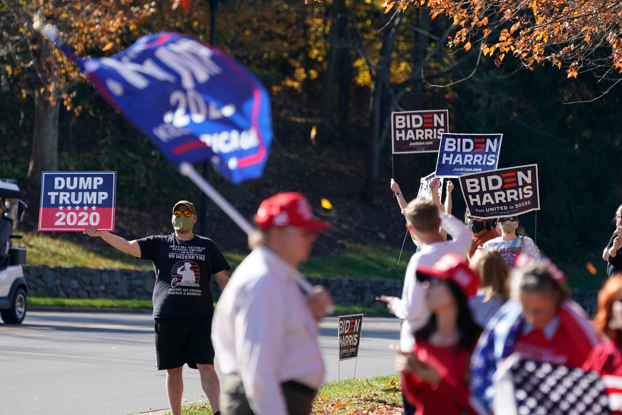 People wave signs and flags at the entrance to Trump National golf club in Sterling, Virginia, on November 7.